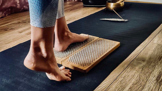 Woman taking her first step onto a Sadhu board during beginner nail board practice