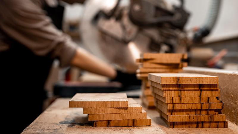 Craftsman working on wooden planks in a workshop, highlighting the meticulous process of creating high-quality Sadhu boards.