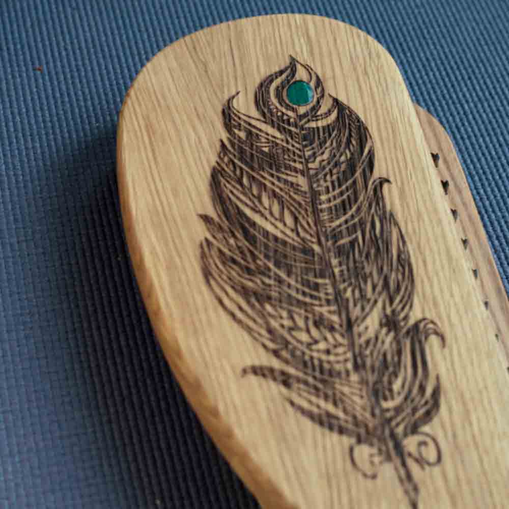 Oak wood sadhu board with a feather design on a blue textured background