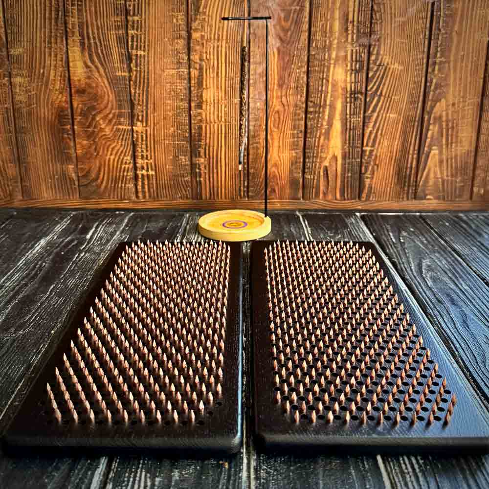 Two sadhu boards with copper nails on a wooden surface
