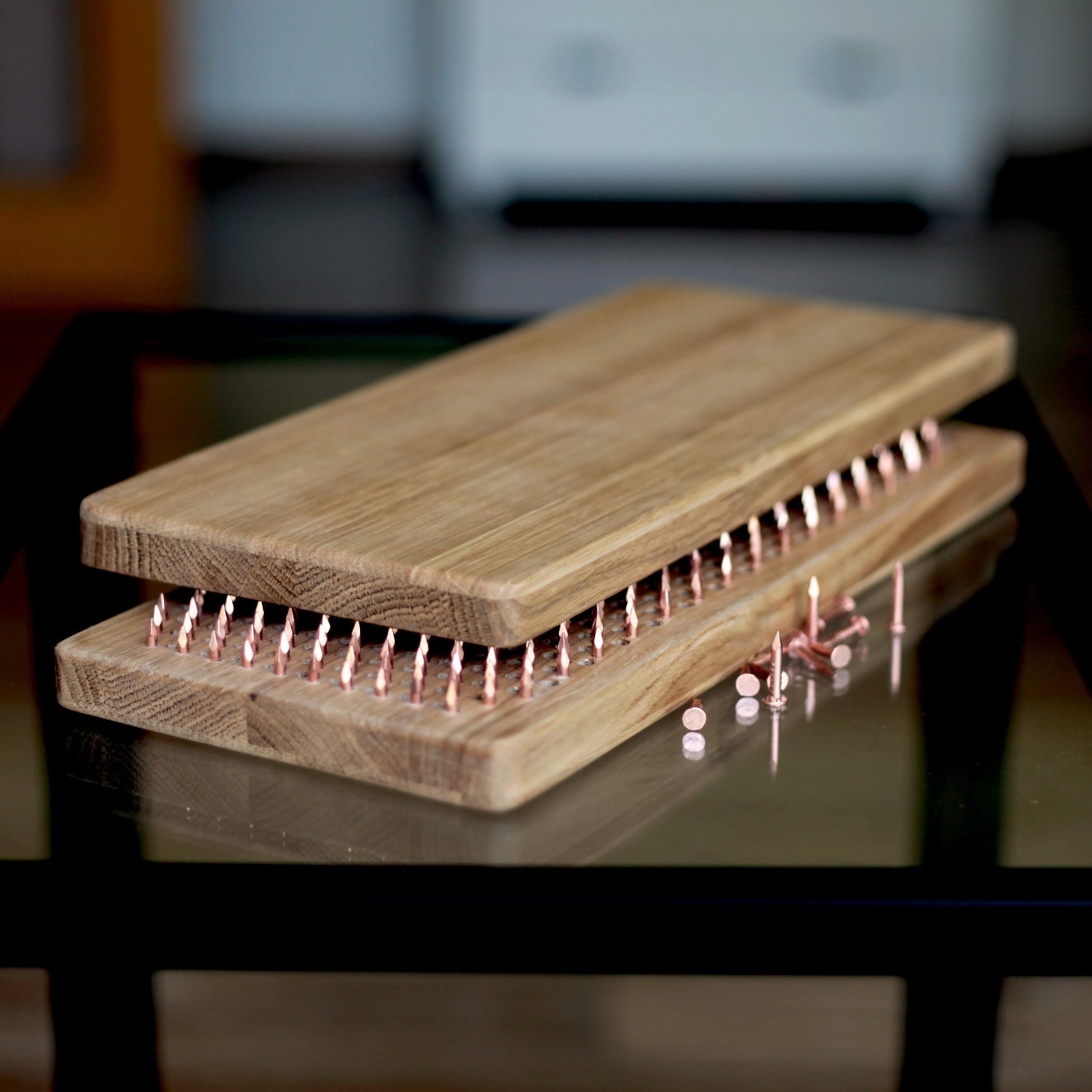 Oak wood sadhu board with copper nails on glass table