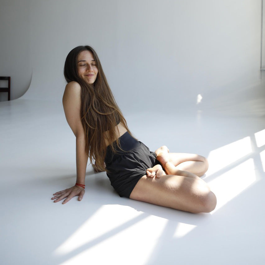 yoga nail board benefits for psychotherapy. yoga girl with happy face after standing on sadhu board nails, sitting in relaxed pose in white room.