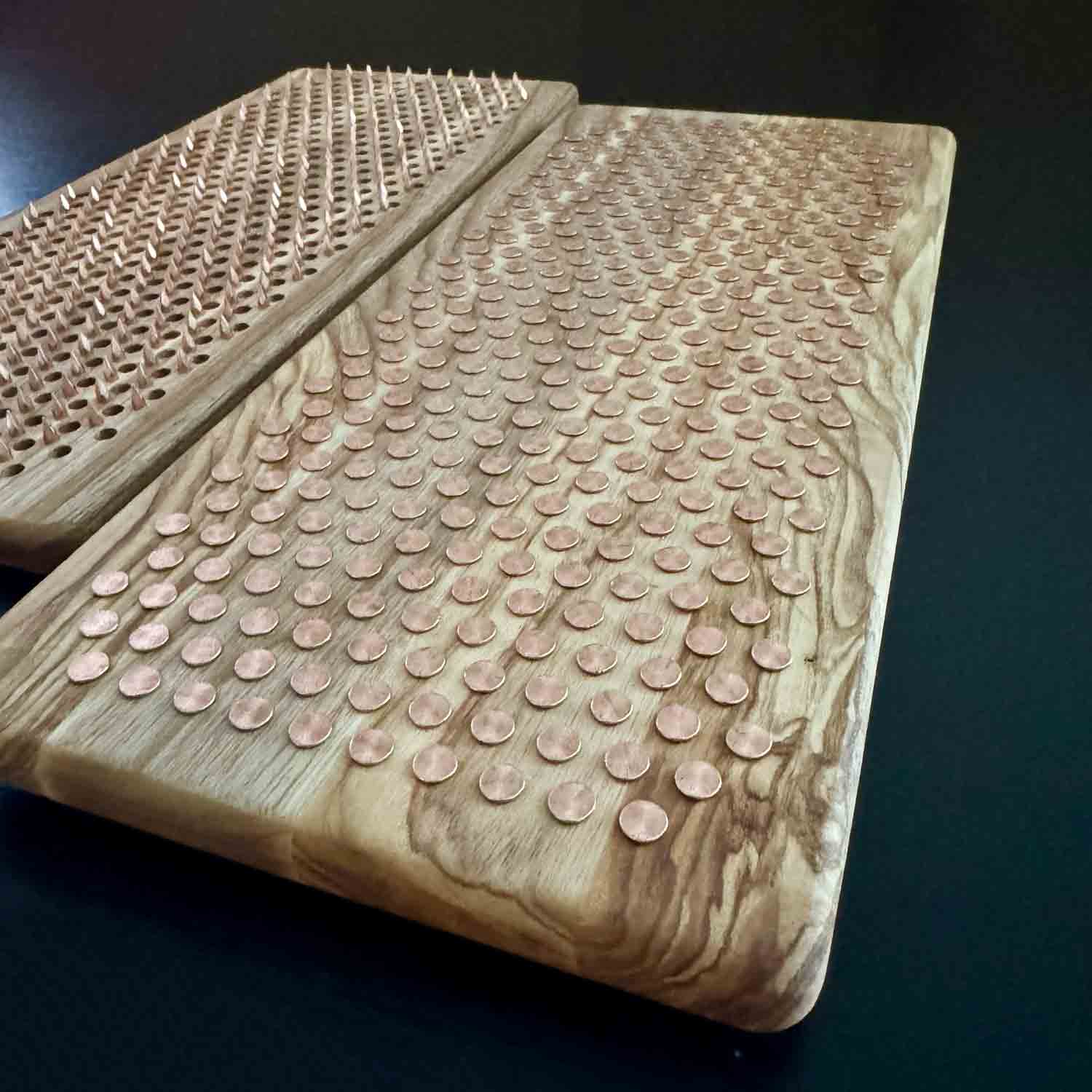 textured natural ash wood sadhu board with copper nails on black background