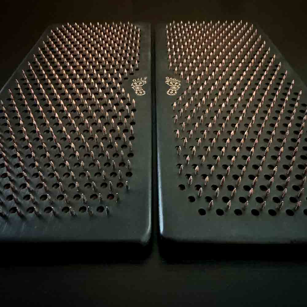 Two black sadhu boards with copper nails with Oh! Sadhu logo on a dark background