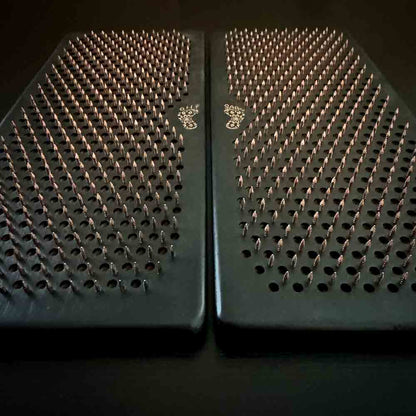 Two black sadhu boards with copper nails with Oh! Sadhu logo on a dark background