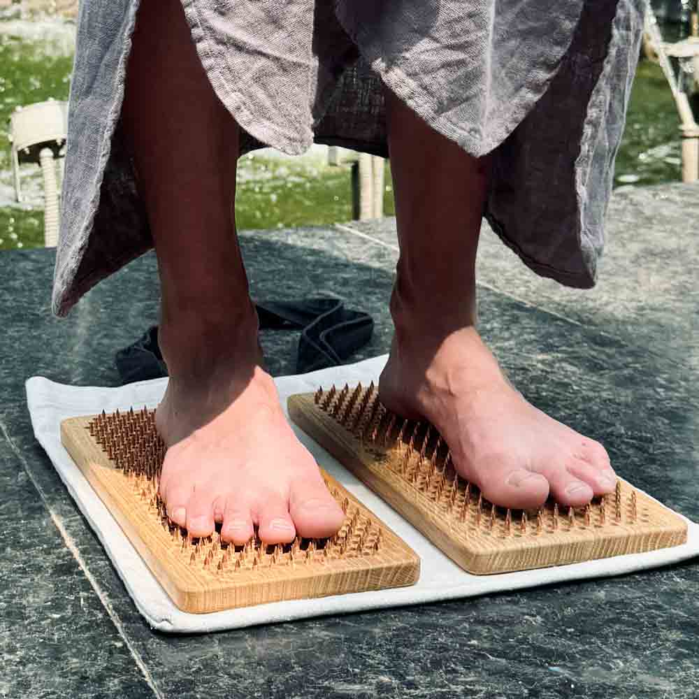 Feet standing on sadhu board made from oak wood and copper nails on stone surface