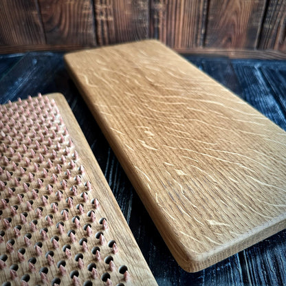 Two handcrafted Sadhu Boards made from natural oak wood, featuring a smooth finish and copper nails. One board is shown with a close-up view of the nail pattern, while the other displays the natural grain and texture of the wood. The boards are set against a dark, rustic wooden background, highlighting their quality craftsmanship and the rich, earthy tones of the oak material.