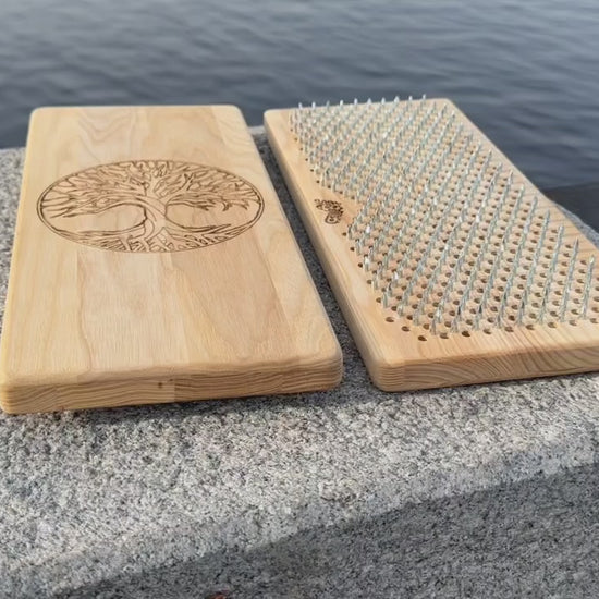 Sadhu board from natural ash wood with tree of life engraving on rock near water. 