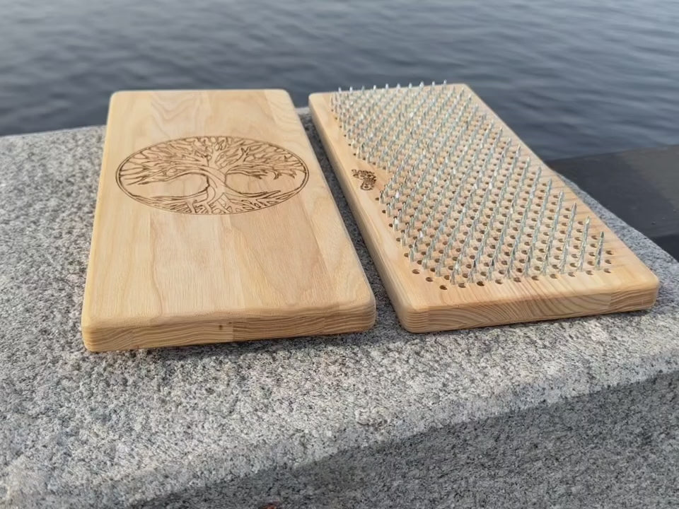 Sadhu board from natural ash wood with tree of life engraving on rock near water. 