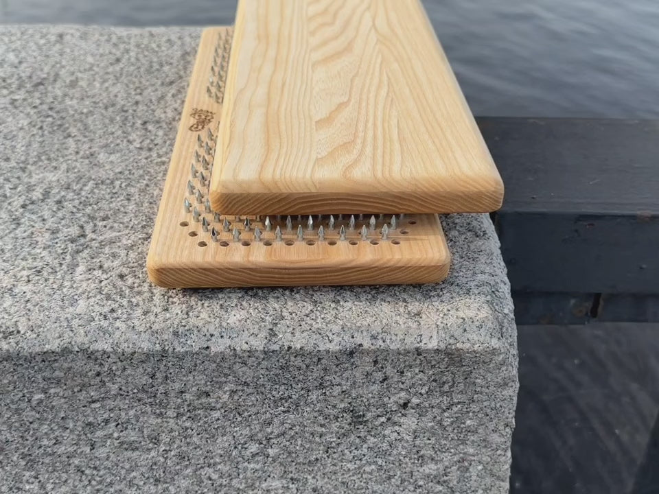 Sadhu board with nails from ash wood placed on rocks near water