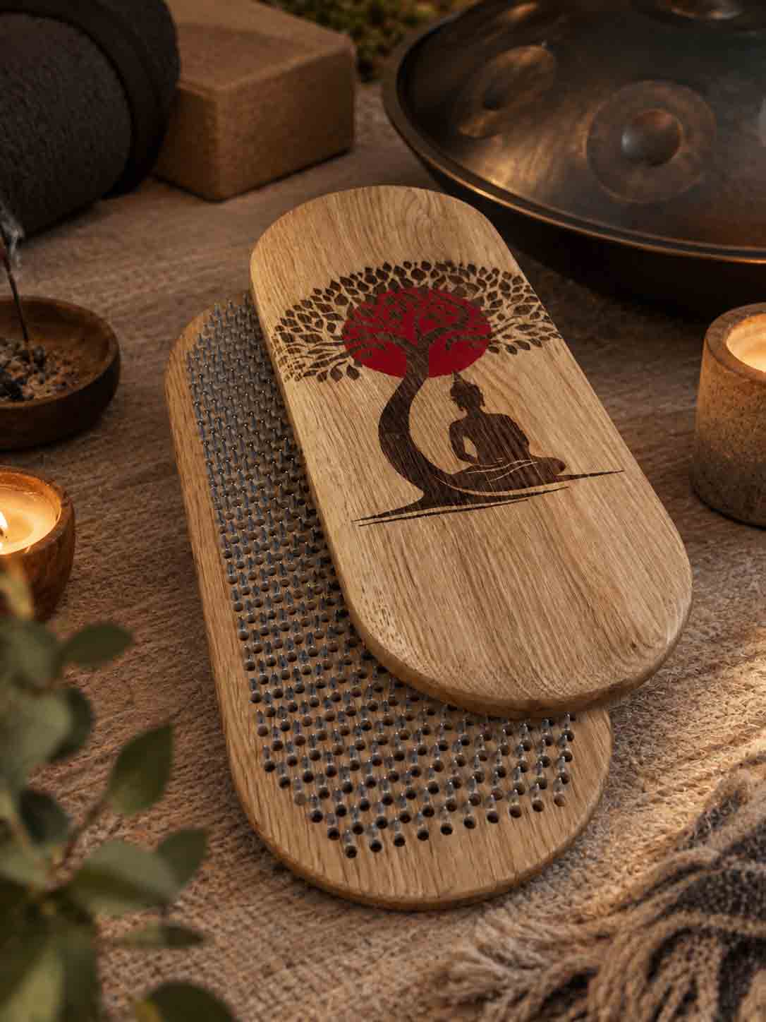 Sadhu board with engraved Buddha sitting under the Bodhi tree with red sun in yoga studio with handpan, candles and other yoga stuff. 