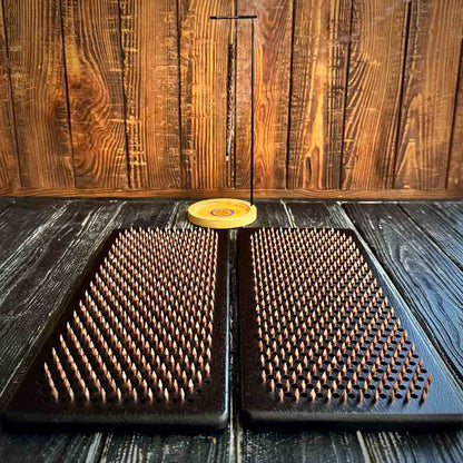 Two sadhu boards with copper nails on a wooden surface