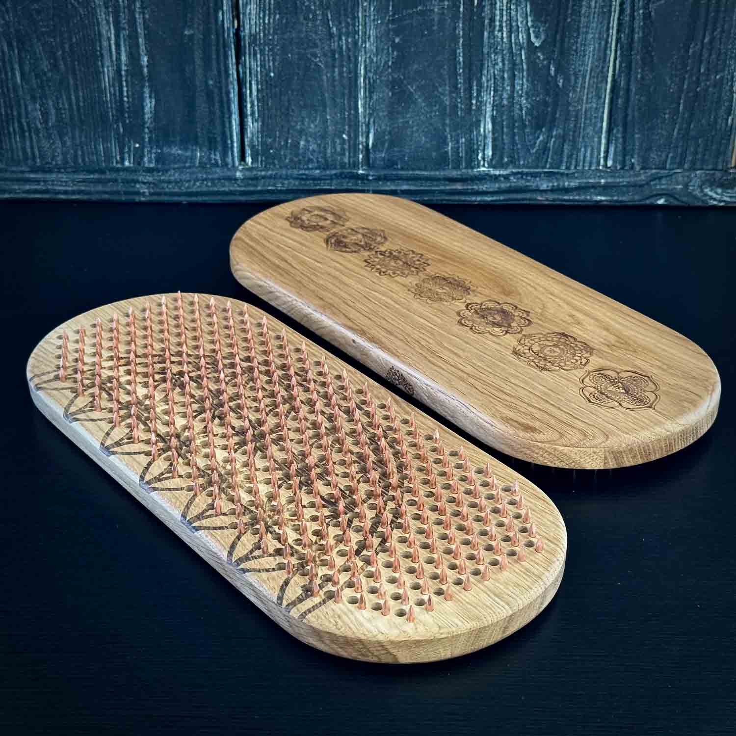Two wooden boards with copper nails for foot on a dark surface.