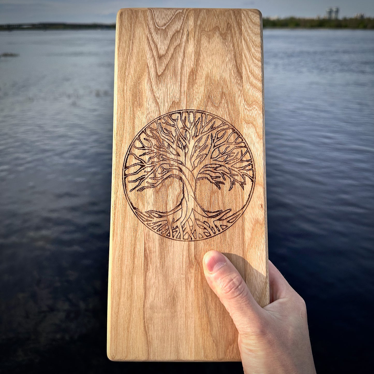 mens hand holding sadhu board from ash wood with tree of life engraving