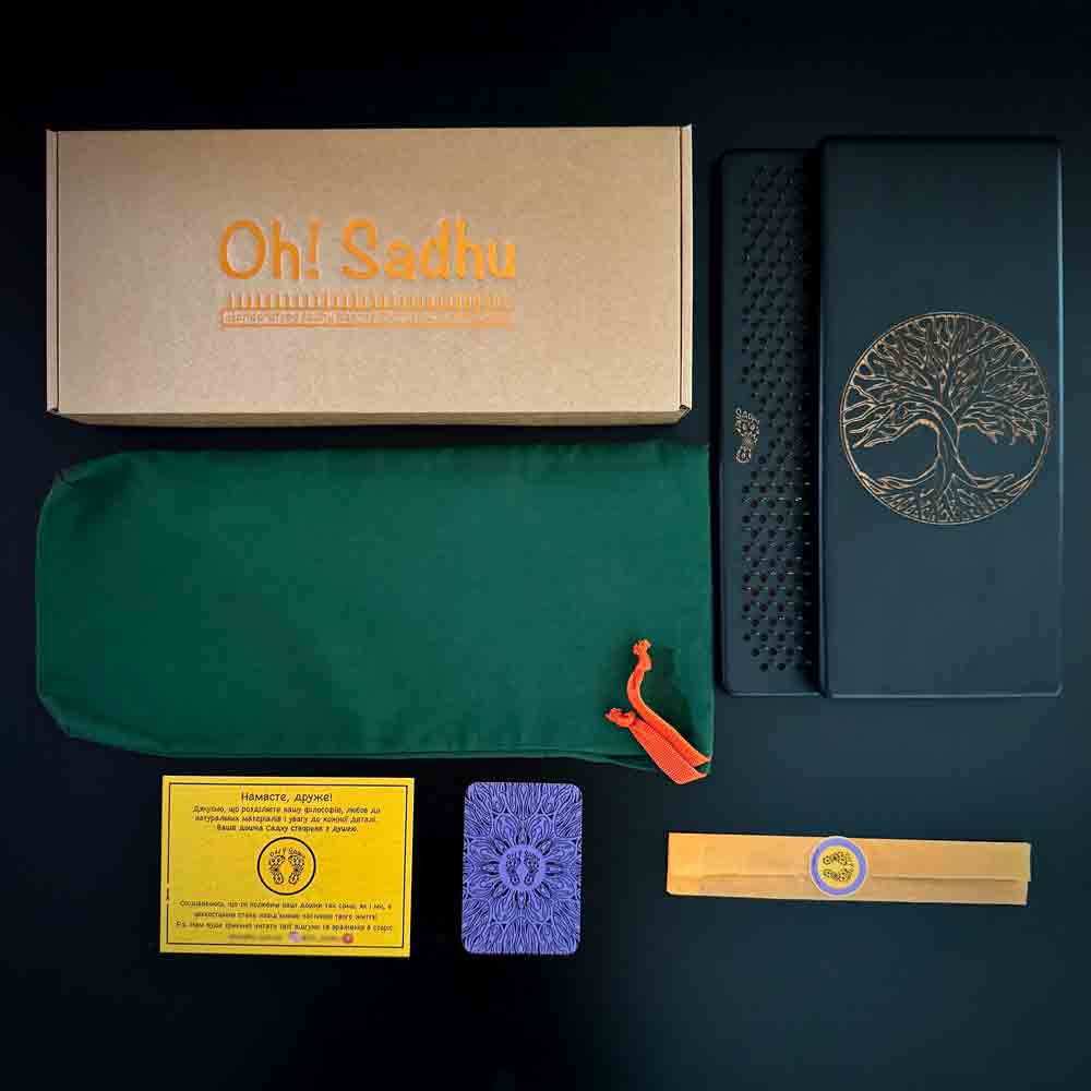 Set of sadhu board with copper nails including a box labeled 'Oh! Sadhu', fabric case, sadhu boards on a dark background