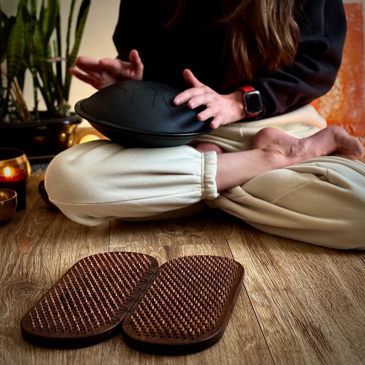 yoga girl playing on hand pan before standing on sadhu board with copper nails